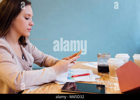 Woman at desk texting on smartphone Stock Photo