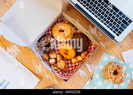 Overhead view of doughnuts in cake box on desk Stock Photo