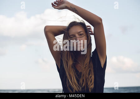 Portrait of young woman with hands raised on beach, Odessa, Odessa Oblast, Ukraine Stock Photo