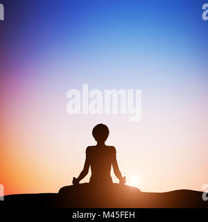 Woman in lotus yoga pose meditating at sunset. Zen Stock Photo