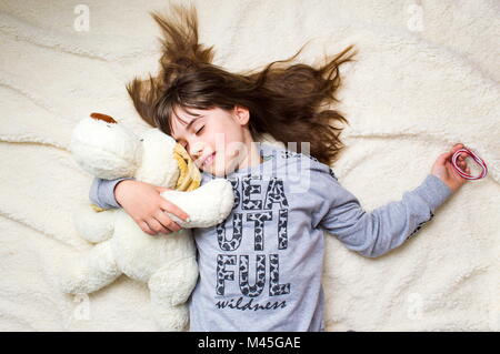 Girl taking a nap while hugging her toy Stock Photo