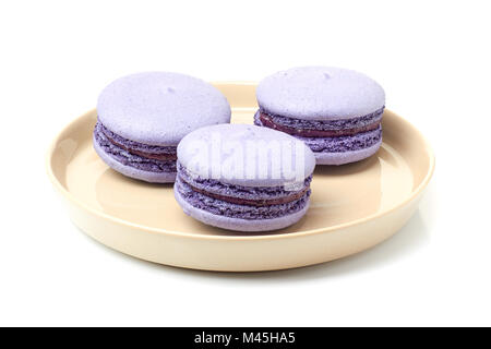 Beige plate with three violet macarons on white Stock Photo