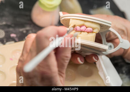 Female Dental Technician Applying Porcelain To A 3D Printed Implant Mold In The Lab. Stock Photo