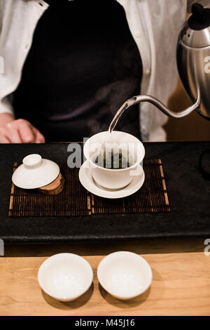 Pouring hot water over tea leaves in teahouse. Stock Photo