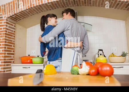 Vegetables on chopping board and couple embracing Stock Photo