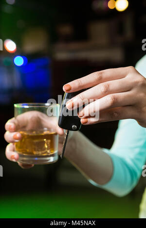 Woman holding a glass of whiskey and car keys