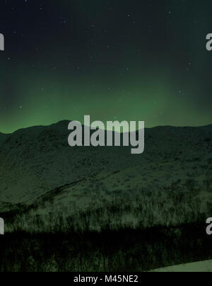 Aurora borealis over snow covered hills at night, Finnmark, Norway Stock Photo