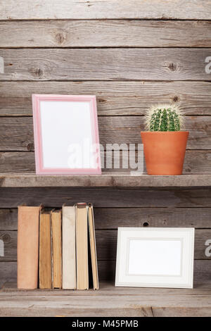 Old books on a wooden shelf, photo frames and cactus plant Stock Photo