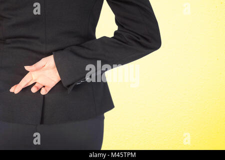 Composite image of businesswoman with fingers crossed behind her back Stock Photo