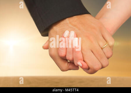 Composite image of newlyweds holding hands close up Stock Photo