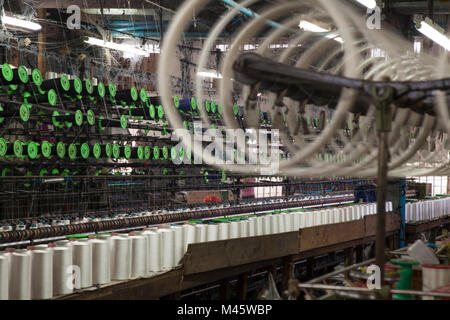 Industrial Machines making cotton threads on spools in fabric factory in Mandalay Myanmar Stock Photo
