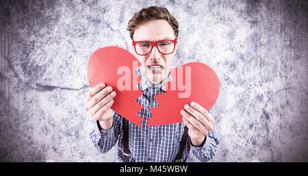 Composite image of geeky hipster holding a broken heart Stock Photo