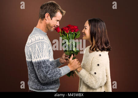 Composite image of romantic couple holding red roses Stock Photo