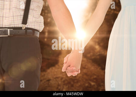 Composite image of hipster couple standing hand in hand Stock Photo