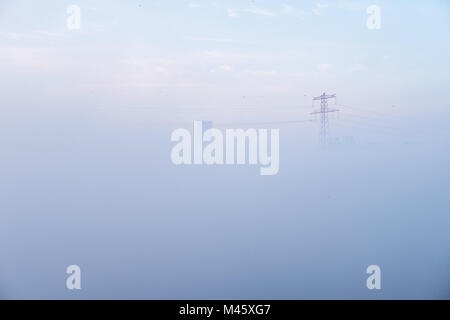 Abu Dhabi covered with the blanket of Dense Fog - Drowned in mist, buildings and Power Towers Peaking through Fog Stock Photo