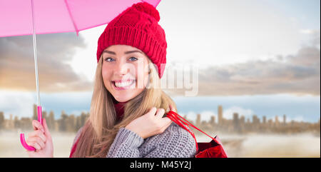 Composite image of festive blonde holding umbrella and bags Stock Photo