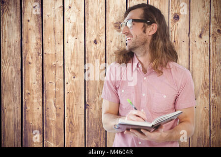 Composite image of happy hipster holding book and pen Stock Photo