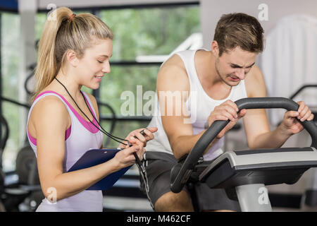 Trainer woman talking with a man doing exercise bike Stock Photo