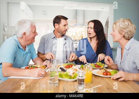 Family discussing while sitting at dining table Stock Photo