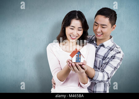 Composite image of happy couple holding a model house Stock Photo