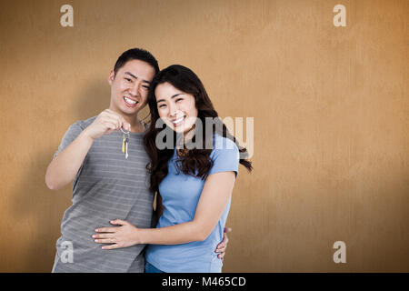 Composite image of portrait of happy young couple with keys Stock Photo