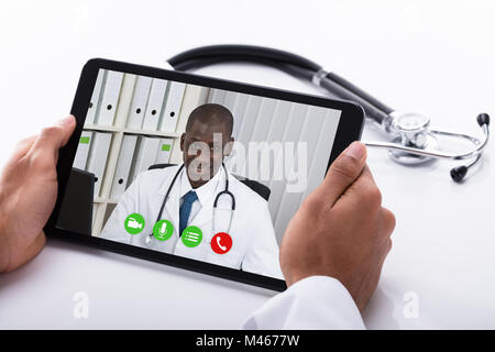 Close-up Of A Doctor's Hand Video Conferencing With African Male Colleague On Digital Tablet Stock Photo