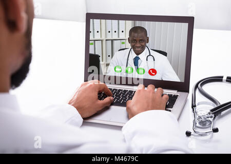 Close-up Of A Doctor's Hand Video Conferencing With African Male Colleague On Laptop Stock Photo