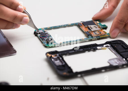 Close-up Of A Technician's Hand Repairing Damaged Smartphone Stock Photo