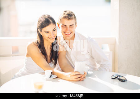 Attractive couple having first date.Coffee with a friend.Smiling happy people making a selfie.Sharing on social media.Showing content on smartphone Stock Photo