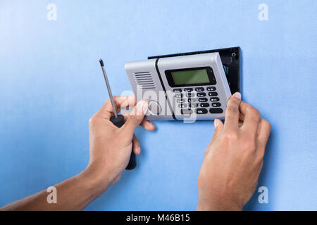 Human Hand Installing Security System On Blue Wall Stock Photo