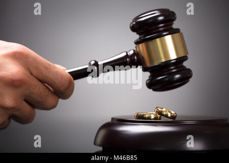 Close-up Of A Judge Hitting Gavel On Golden Rings In Courtroom Stock Photo