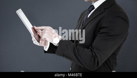 Composite image of businessman in suit using digital tablet Stock Photo