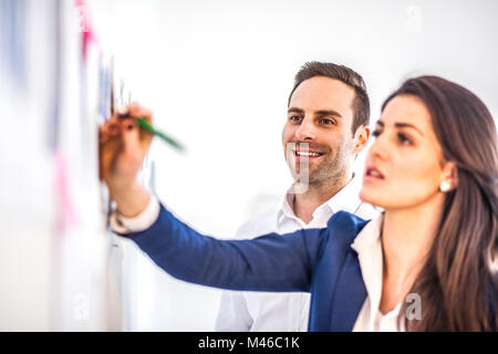 Smiling young businessman with female colleague brainstorming in creative office Stock Photo