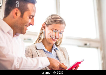 Smiling young business people discussing over diary in office Stock Photo