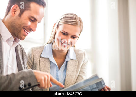 Smiling young business people discussing over brochure in office Stock Photo