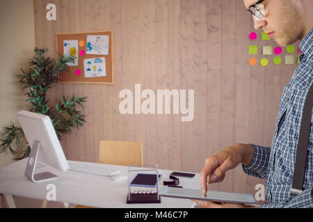 Composite image of geeky businessman using his tablet pc Stock Photo