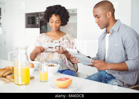 Smiling couple reading magazine and documents during breakfast Stock Photo