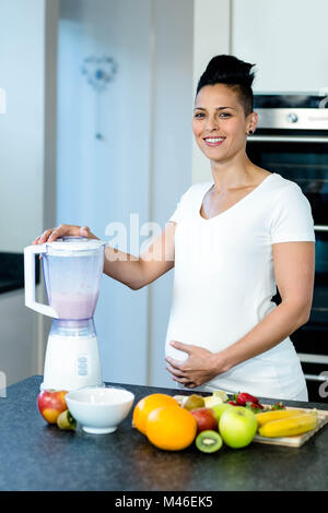 Pregnant woman preparing fruit juice in blender Stock Photo