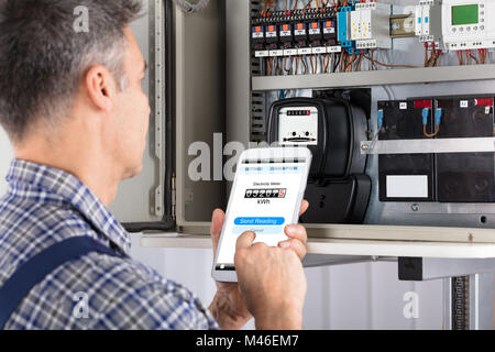 Close-up Of A Male Technician Doing Meter Reading Using Mobilephone Stock Photo