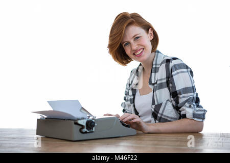 smiling hipster woman typing on her typewriter Stock Photo