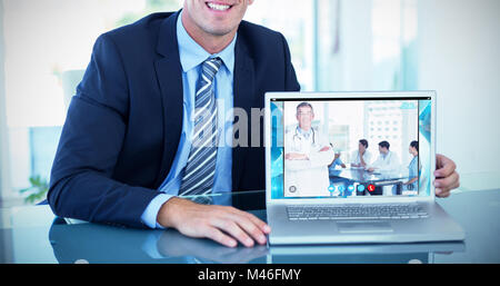 Composite image of portrait of smiling businessman showing laptop Stock Photo