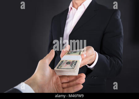 Close-up Of A Businessman Receiving A Bank Note On Black Background Stock Photo