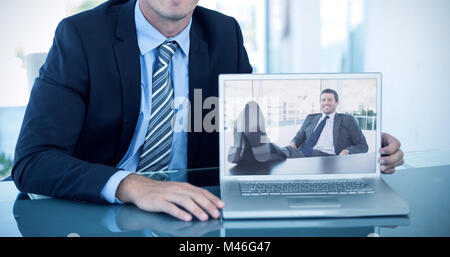 Composite image of portrait of smiling businessman showing laptop Stock Photo