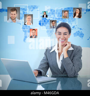 Composite image of cheerful businesswoman using laptop at desk Stock Photo
