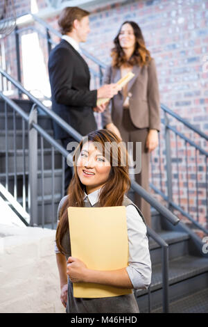 Businesswoman standing near staircase with documents Stock Photo