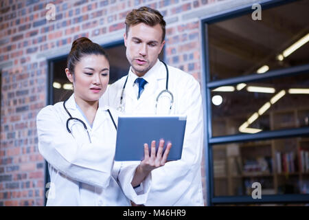 Doctors discussing over digital tablet near library Stock Photo
