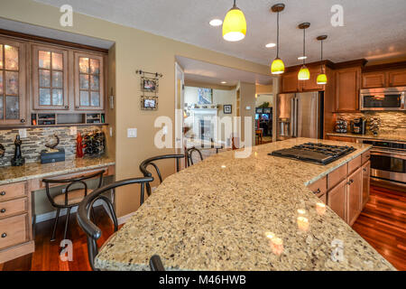 An upscale kitchen with granite slab countertops, hardwood flooring, stainless appliances and extra large center island. Stock Photo