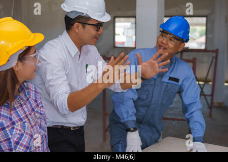 Engineer is explaining work to technician and female worker at a construction site in Bangkok, Thailand. Stock Photo
