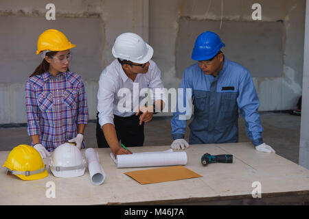 Engineer is explaining work to technician and female worker at a construction site in Bangkok, Thailand. Stock Photo