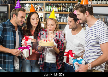 Woman blowing out candles while friends watch Stock Photo